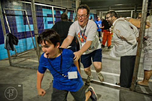 Dan Hunt (center) and his son Shamus (front) run past Daniel Corbett (right) and other walkers during The Walking Dead Escape event at Philips Arena in Atlanta on Saturday, May 31, 2014.