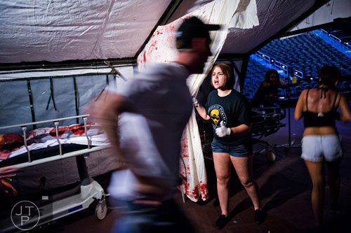 Meghan Baptie (center) yells at participants to keep moving as they make their way past walkers during The Walking Dead Escape event at Philips Arena in Atlanta on Saturday, May 31, 2014. 