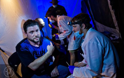 Chris Hornby (left) has his infection level checked by Luke Tieslau as he completes The Walking Dead Escape event at Philips Arena in Atlanta on Saturday, May 31, 2014. 