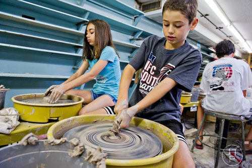 Owen Ross (right) and Melissa Rinzler use wheels to throw clay pots during Summer Youth Art Weeks at the Abernathy Arts Center in Sandy Springs on Wednesday, June 4, 2014.  