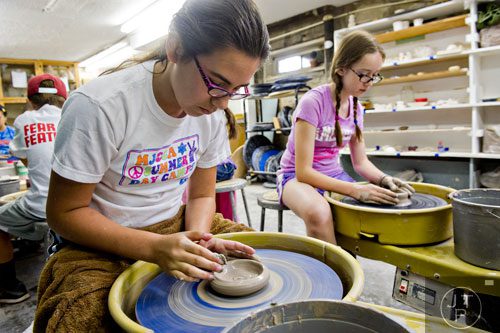 Izzy Martinez (left) and Sarah Davis use wheels to throw clay pots during Summer Youth Art Weeks at the Abernathy Arts Center in Sandy Springs on Wednesday, June 4, 2014.  