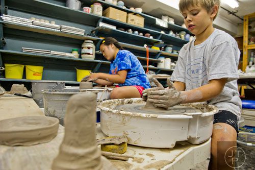 Noah Piontek (right) and Ainslee Coombs use wheels to throw clay pots during Summer Youth Art Weeks at the Abernathy Arts Center in Sandy Springs on Wednesday, June 4, 2014. 