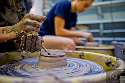 Sam Ivey (left) molds clay on a wheel during Summer Youth Art Weeks at the Abernathy Arts Center in Sandy Springs on Wednesday, June 4, 2014.  
