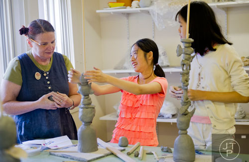 Instructor Red Weldon (left) talks with Allison Lu and Cynthia Peng as they build clay totems during Summer Youth Art Weeks at the Abernathy Arts Center in Sandy Springs on Wednesday, June 4, 2014. 