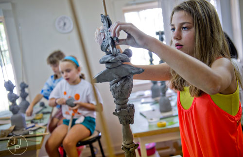 Jaden Godbout stacks clay figurines as she builds a totem during Summer Youth Art Weeks at the Abernathy Arts Center in Sandy Springs on Wednesday, June 4, 2014. 