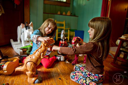 Makenzie Hoff (right) and her twin sister Madeline play with toy dinosaurs while on a lunch break during Beach Week at the Farmhouse in the City in Roswell on Wednesday, June 4, 2014.  