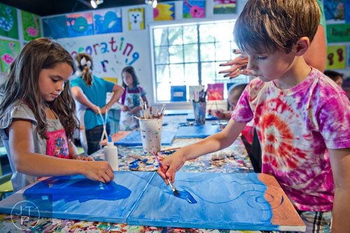 Kaya Moore (left) and Noah Diamond paint seahorses on pieces of canvas during Beach Week at the Farmhouse in the City in Roswell on Wednesday, June 4, 2014.  