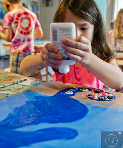 Jolie Thaler glues butons onto a canvas as she makes a multimedia seahorse during Beach Week at the Farmhouse in the City in Roswell on Wednesday, June 4, 2014.  