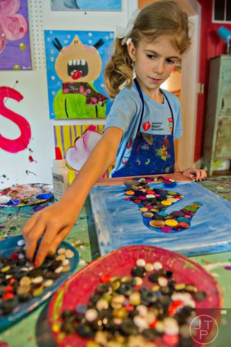 Haley Saulinskas reaches for buttons as she makes a multimedia seahorse during Beach Week at the Farmhouse in the City in Roswell on Wednesday, June 4, 2014.  