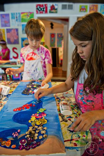 Kaya Moore (right) and Noah Diamond glue butons onto pieces of canvas as they make multimedia seahorses during Beach Week at the Farmhouse in the City in Roswell on Wednesday, June 4, 2014.  