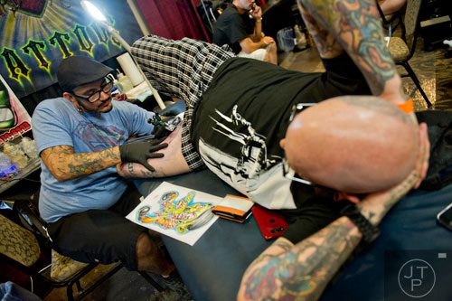 Eddy Arg (left) tattoos Chris Emory's inner thigh during the Atlanta Tattoo Expo at the Wyndham Atlanta Galleria hotel on Saturday, June 7, 2014. 