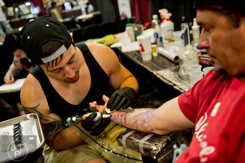 Wil Hilderbrand (left) works on a new tattoo on James Knight's arm during the Atlanta Tattoo Expo at the Wyndham Atlanta Galleria hotel on Saturday, June 7, 2014.