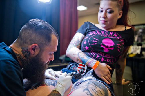 Jay Bargoil (left) tattoos Alexis Johns' leg during the Atlanta Tattoo Expo at the Wyndham Atlanta Galleria hotel on Saturday, June 7, 2014. 