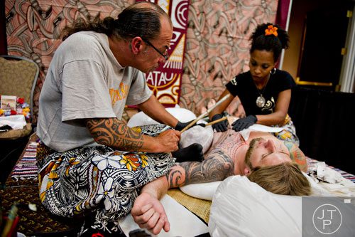 Pili Mo'o Tatau (left) and Penina Samo'o (right) work a traditional Samoan tattoo on Jason Eller's chest during the Atlanta Tattoo Expo at the Wyndham Atlanta Galleria hotel on Saturday, June 7, 2014. 