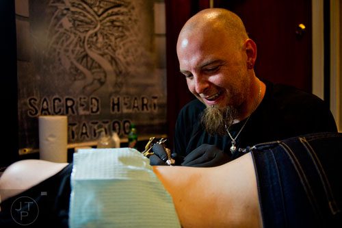 K.C. Wagner (right) tattoos Dana Kelso's ribcage during the Atlanta Tattoo Expo at the Wyndham Atlanta Galleria hotel on Saturday, June 7, 2014. 