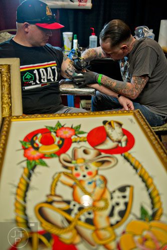 Josh Lindley (right) tattoos Charlie Solonka's arm during the Atlanta Tattoo Expo at the Wyndham Atlanta Galleria hotel on Saturday, June 7, 2014. 