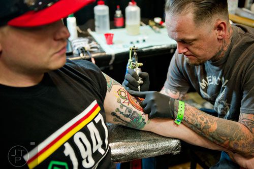 Josh Lindley (right) tattoos Charlie Solonka's arm during the Atlanta Tattoo Expo at the Wyndham Atlanta Galleria hotel on Saturday, June 7, 2014.