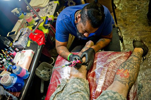 Craig Foster (top) tattoos Christopher Smith's leg during the Atlanta Tattoo Expo at the Wyndham Atlanta Galleria hotel on Saturday, June 7, 2014. 