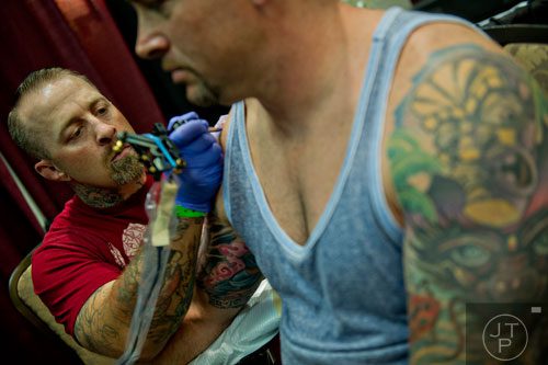 Josh Ford (left) touches up one of Scott McCown's ten tattoos during the Atlanta Tattoo Expo at the Wyndham Atlanta Galleria hotel on Saturday, June 7, 2014. 
