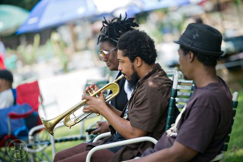 Dashill Smith (center) plays the trumpet as he sits with Reisha Lauren and Javon Brothers Jr. during the Patchwork City Farms' Father's Day Farm Fete in Atlanta on Sunday, June 15, 2014. 
