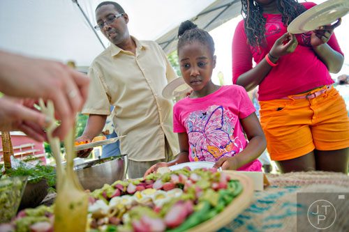 Grace Muigai (center) and her father Paul (left) are served lunch during the Patchwork City Farms' Father's Day Farm Fete in Atlanta on Sunday, June 15, 2014. 