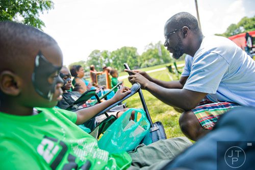 Kenneth Bowden (right) takes photos of his two sons, Zachary (left) and Xavier, during the Patchwork City Farms' Father's Day Farm Fete in Atlanta on Sunday, June 15, 2014. 