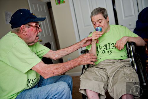 Alvin McGarity (left) helps his son Keith with a cup of fruit punch at the Southern Community Living Group home in McDonough on Sunday, June 15, 2014. 