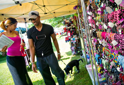 Tammi Douglas (left) and her husband Jason buy a harness for their newly adopted puggle during the Art, Barks & Purrs Arts and Crafts Festival at the Cobb County Animal Control facility in Marietta on Saturday, June 21, 2014. 
