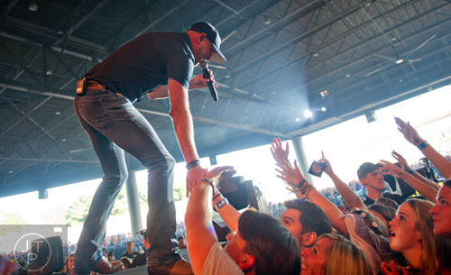 Cole Swindell gives high fives to fans as he performs on stage at Aaron's Amphitheatre at Lakewood in Atlanta on Friday, July 25, 2014. 