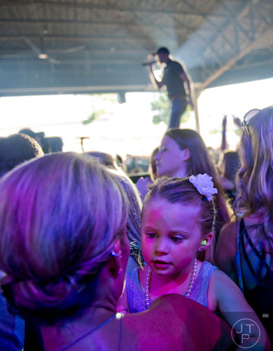 Blakely Everette (right) is held by her mother Shelly as they listen to Cole Swindell as he performs on stage at Aaron's Amphitheatre at Lakewood in Atlanta on Friday, July 25, 2014.  