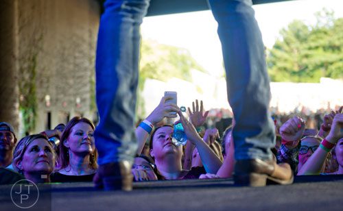 Dana Brown (center) takes a photo of Cole Swindell as he performs on stage at Aaron's Amphitheatre at Lakewood in Atlanta on Friday, July 25, 2014.  