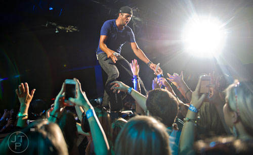 Luke Bryan gives out high fives to fans as he performs on stage during his That's My Kind of Night Tour at Aaron's Amphitheatre at Lakewood in Atlanta on Friday, July 25, 2014.  