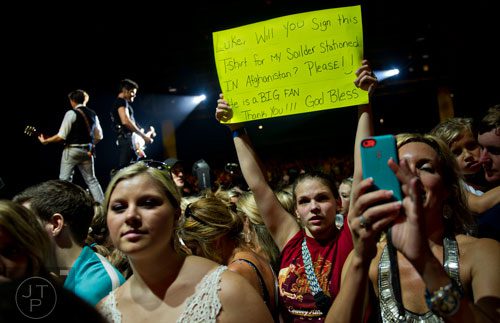 Robyn Dillard (center) holds up a sign as Luke Bryan performs on stage during his That's My Kind of Night Tour at Aaron's Amphitheatre at Lakewood in Atlanta on Friday, July 25, 2014. 