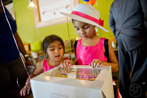 Two of Bounkham Phonesavanh's sisters Emma (right) and Malee look at a cake for their brother during a farewell breakfast at Delightful Eatz in Atlanta on Wednesday, July 2, 2014. 