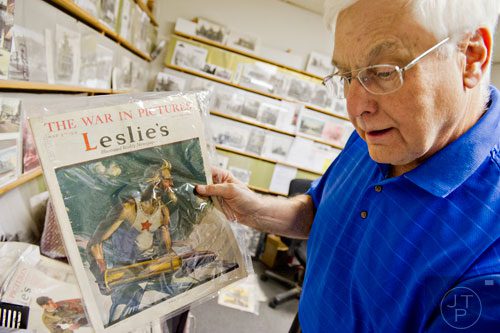 Steve Ehrlich holds up copies of Leslie's Illustrated Weekly Newspaper in his office in Marietta as he explains how the covers were created from 1917-1918 to garner support for World War I on Wednesday, July 2, 2014.