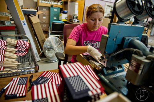 Lorena Hernandez staples an American flag onto a stake at U.S. Flag Makers in Marietta on Wednesday, July 2, 2014. 