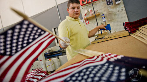 Rosendo Flores places an American flag into a pile at U.S. Flag Makers in Marietta on Wednesday, July 2, 2014.  