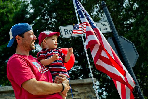 Will Britt (left) holds his son David as they wait for the start of the Marietta Freedom Parade on Friday, July 4, 2014. 