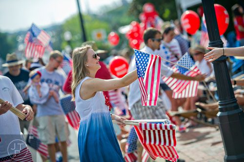 Rachel Dietz (center) hands out American flags before the start of the Marietta Freedom Parade on Friday, July 4, 2014. 