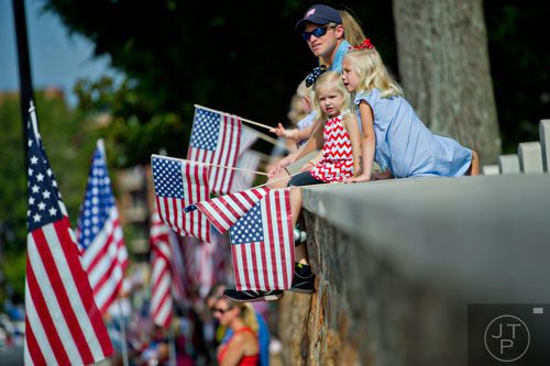Ella Carr (right) sits with her sister Lizette and father Adam as they wait for the start of the Marietta Freedom Parade on Friday, July 4, 2014. 