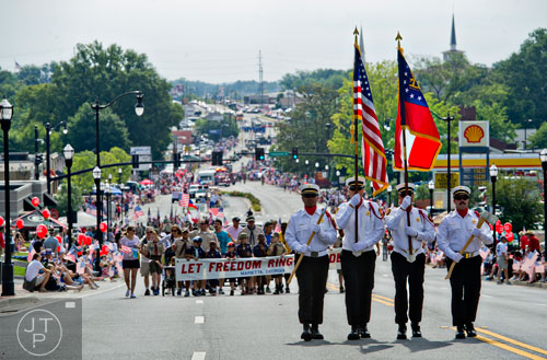 Members of the Marietta Fire Department Honor Guard march up Roswell St. during the Marietta Freedom Parade on Friday, July 4, 2014.