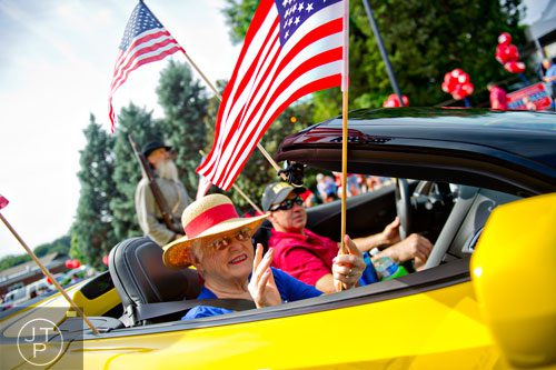 Grand Marshall Betty Hunter waves an American flag as she rides in a convertible towards Historic Marietta Square during the city's  Freedom Parade on Friday, July 4, 2014. 
