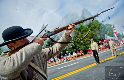 Jeff Wright with the Sons of Confederate Veterans fires his rifle into the air as he marches down Roswell St. and towards Historic Marietta Square during the city's Freedom Parade on Friday, July 4, 2014. 