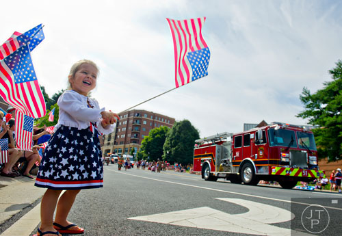 Kylee Arnold waves an American flag as she watches the Marietta Freedom Parade move down Roswell St. on Friday, July 4, 2014. 