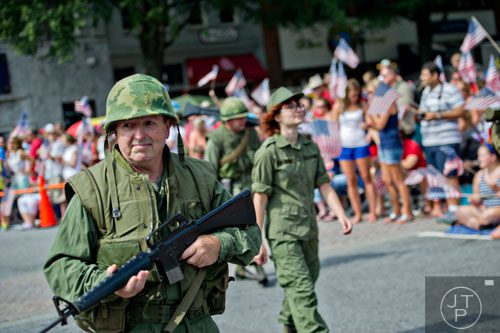 Carey Woodall (left) carries his rifle as he marches through Historic Marietta Square during the city's Freedom Parade on Friday, July 4, 2014. 
