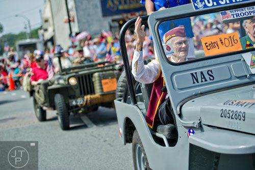 Ronald Scott waves to the crowd as he rides in a restored Navy jeep through Historic Marietta Square during the city's Freedom Parade on Friday, July 4, 2014. 