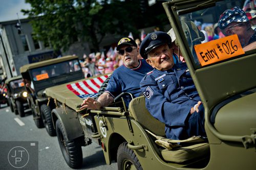 Larry Abel (right) and Ira Giles ride in a restored Army jeep as they make their way through Historic Marietta Square during the city's  Freedom Parade on Friday, July 4, 2014. 