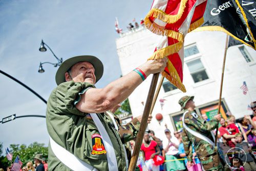 Dressed in Vietnam era combat gear, Al Heflin carries an American flag as he marches through Historic Marietta Square during the city's  Freedom Parade on Friday, July 4, 2014. 