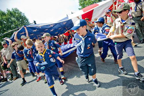 Boy Scout David McNeil (right) and cub scouts Derek Stutz and Ayden Matthews pull a smaller American flag out from under a larger on as they march through Historic Marietta Square during the city's  Freedom Parade on Friday, July 4, 2014. 