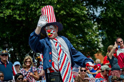 Bill Carver waves to the crowd as he marches through Historic Marietta Square during the city's  Freedom Parade on Friday, July 4, 2014. 